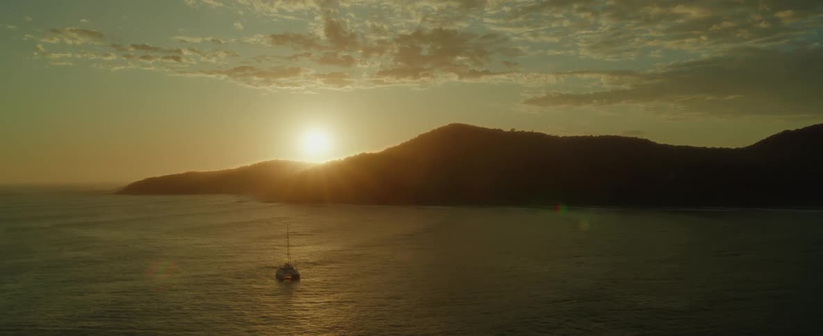 A gentle ocean flowing towards the right with clouds adorning the evening sky