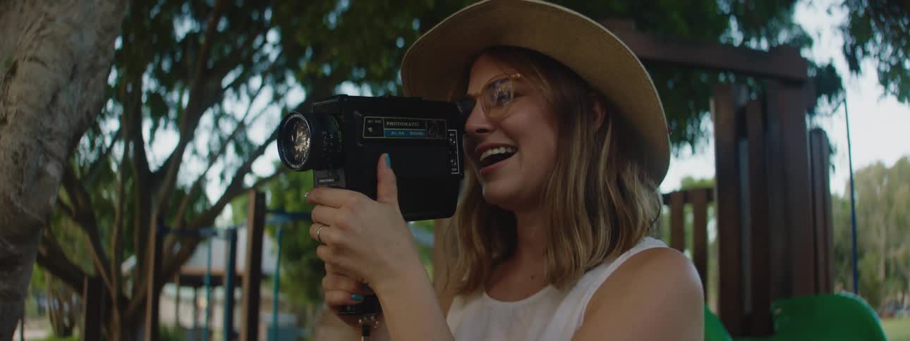 Mom taking home movies at park of toddler daughter off camera during the day