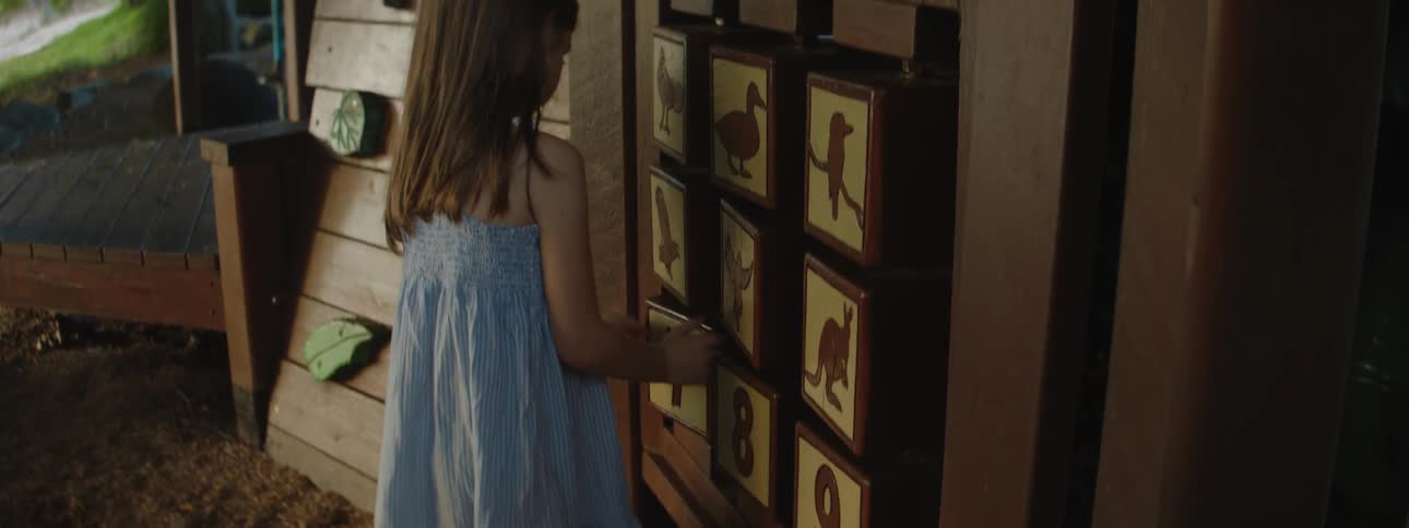 A young girl standing in front of a wooden matching game as she turns the pieces
