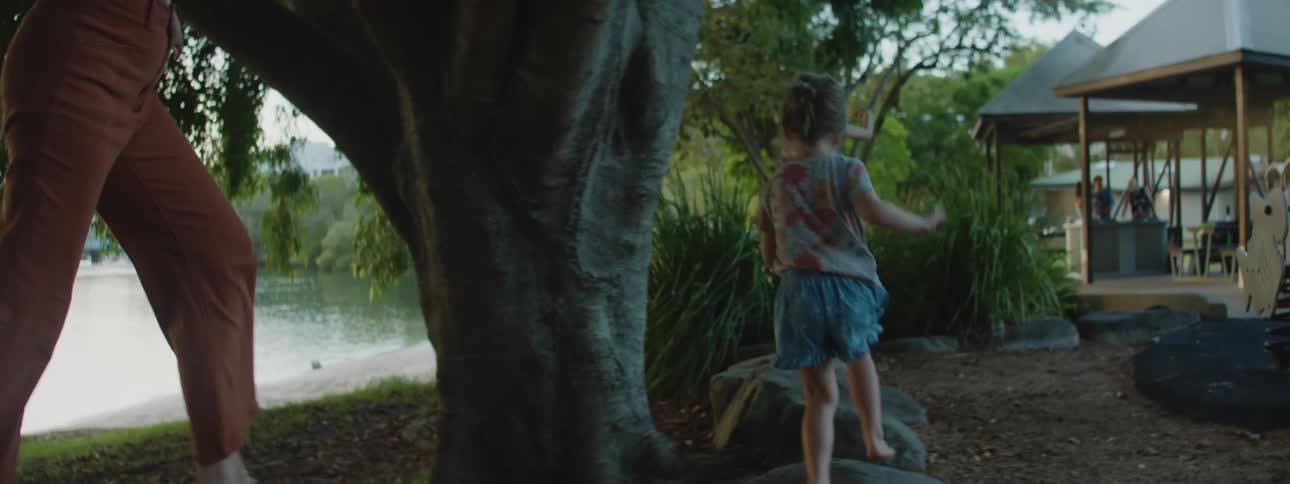 Woman plays stepping stones with her daughters near a lake on a park at daytime