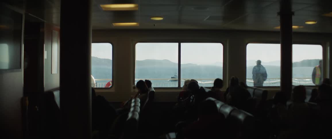 Men stand outside on a ship looking at the water