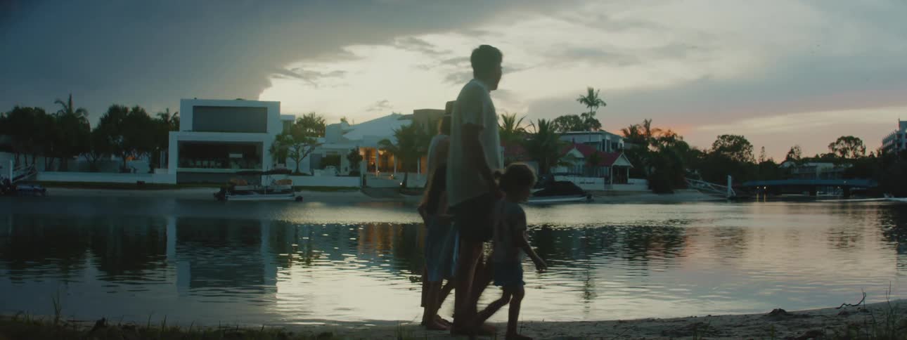Father mother and two daughters walking holding hands along a shoreline