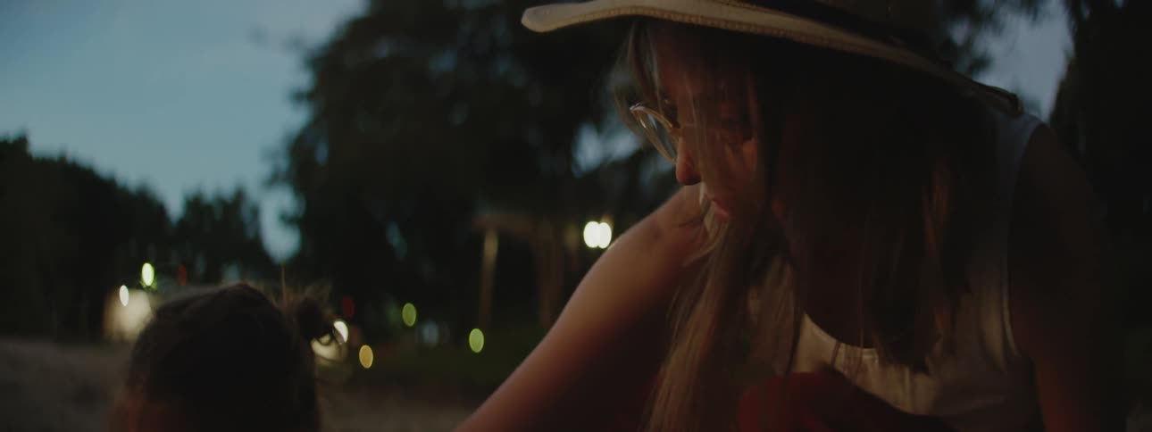 Mother and toddler girl playing in a sandbox at a playground at sundown early evening