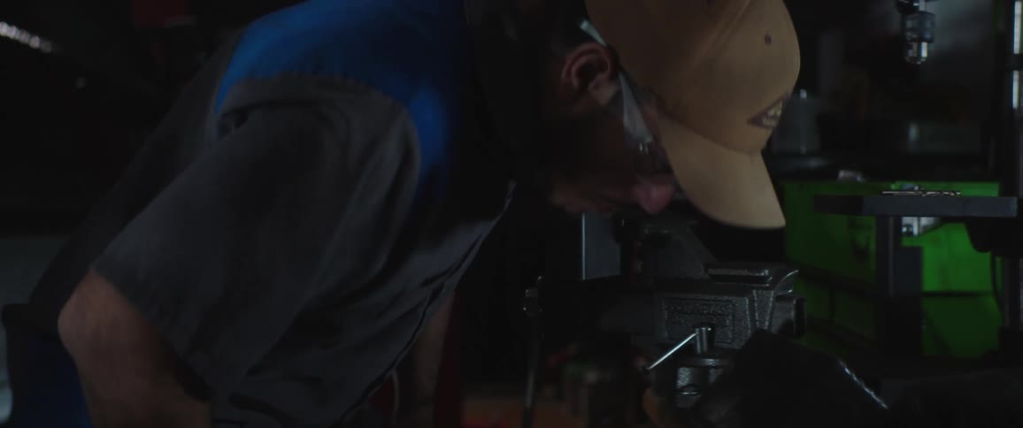 A man puts on safety glasses before sitting down and picking up a tool