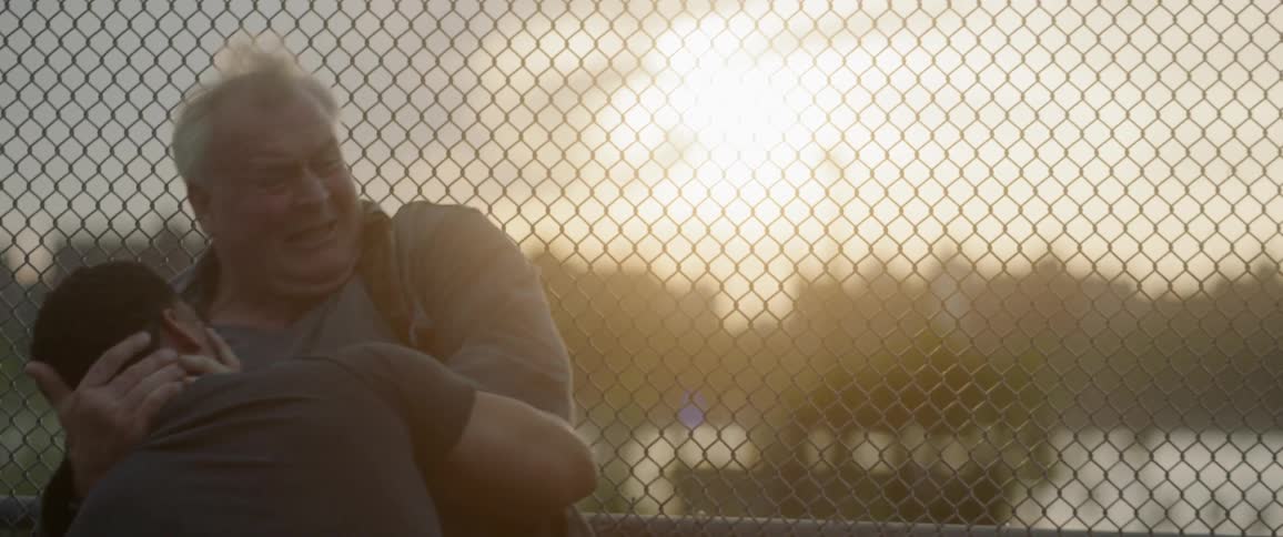Two men fighting and punching each other next to a fence