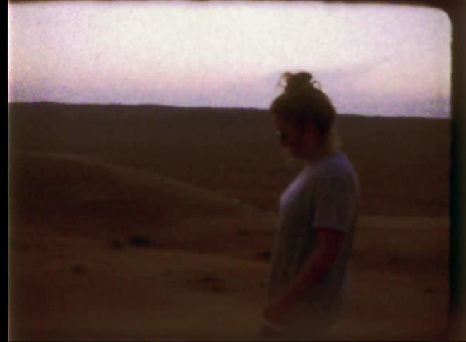 Vintage film of a woman is walking slowly through the desert