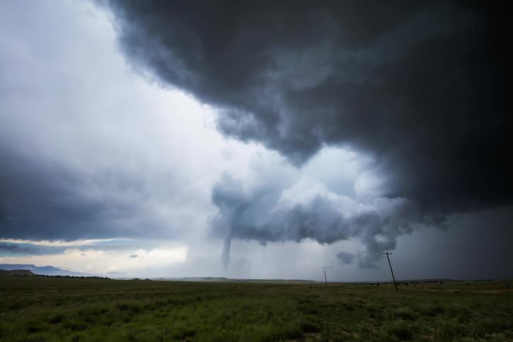 Very dark clouds spinning and billowing above an empty field