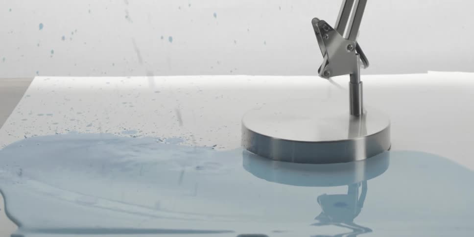 Blue liquid splashing into a small pool with a metal object nearby