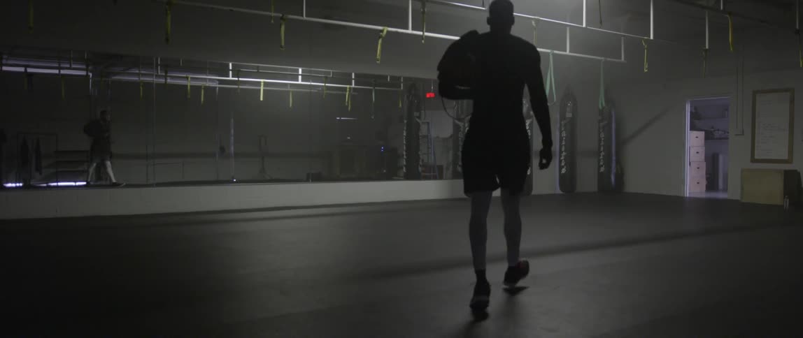 A man walks across the gym toward the heavy bags