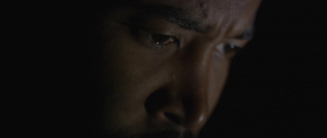A man is looking down in dark area