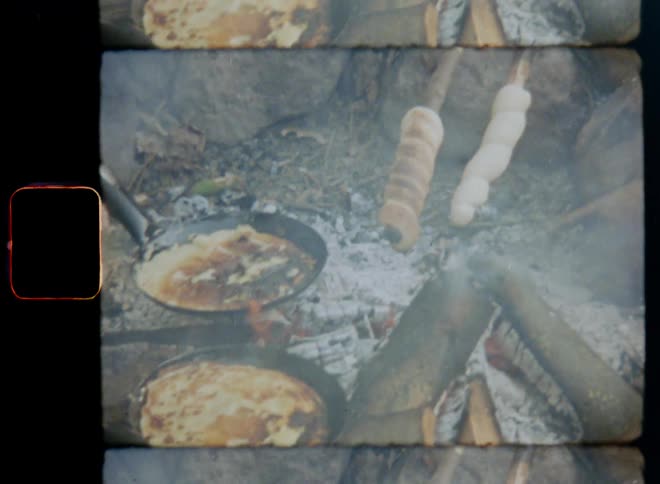 Smoke rises as food is cooked over open campfire