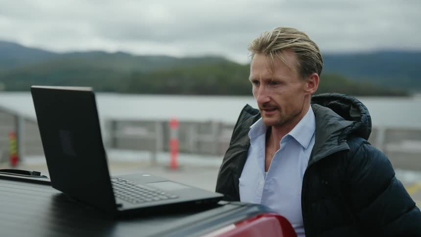 A man is typing on his keyboard outside