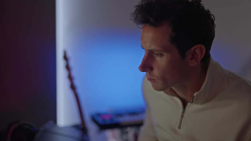 A man is playing the guitar at his computer