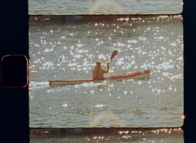 Old footage of person paddling a canoe on a lake