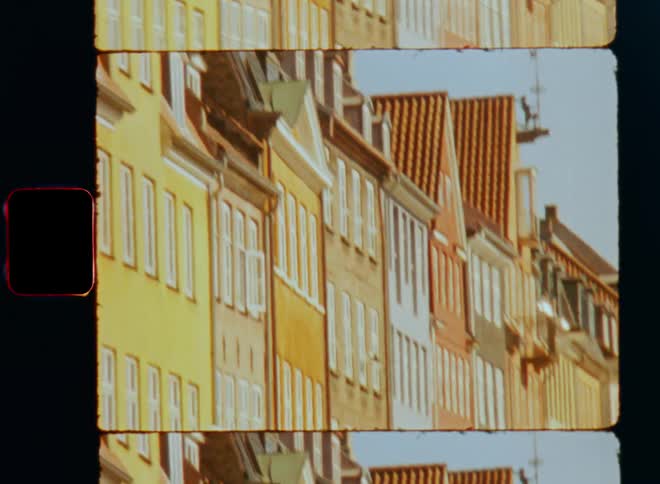 Row of row houses in different colors stand under clear blue sky