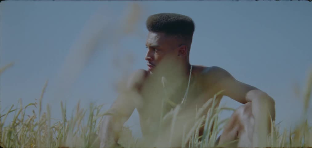 Introspective black man sitting on the grass on a sunny day