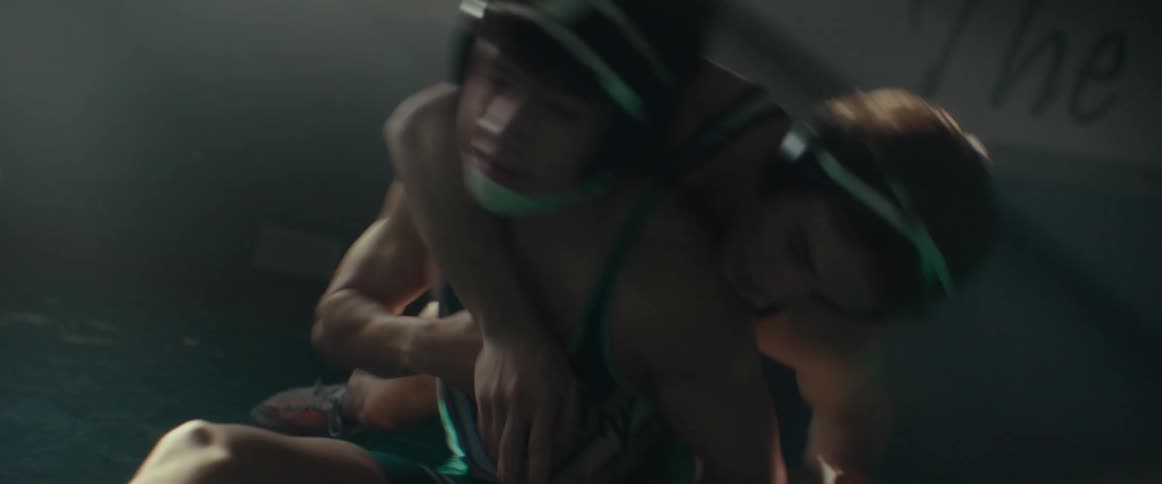 Young men wearing wrestling clothes practicing wrestling in an empty gymnasium