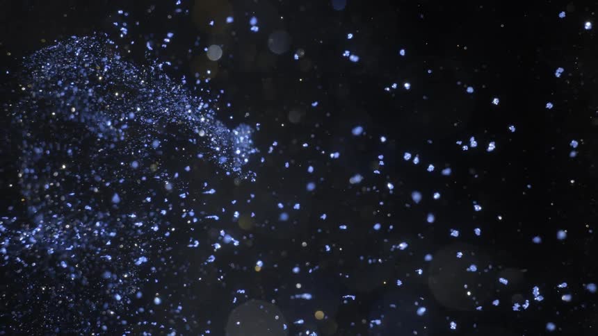 Blue particles floats through darkness sprinkled with light spots and dots