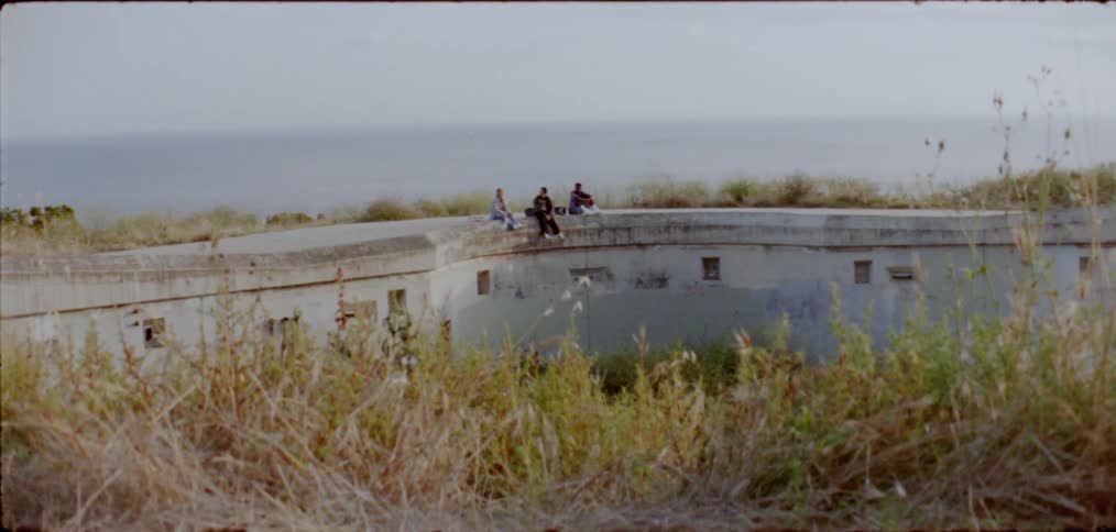 Three people sit on the building on the mountain