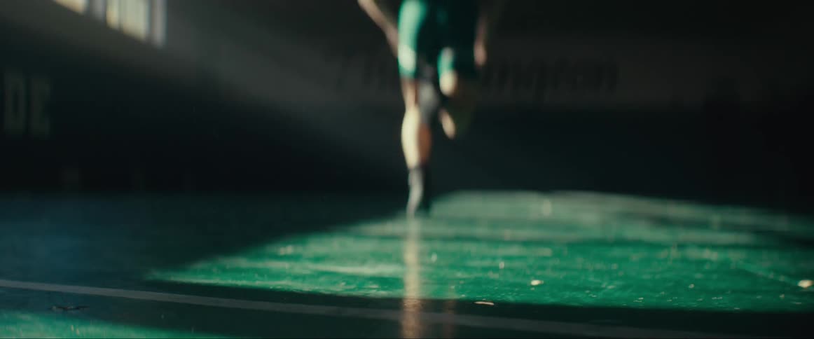 A young man training by running in an empty sunlit gymnasium