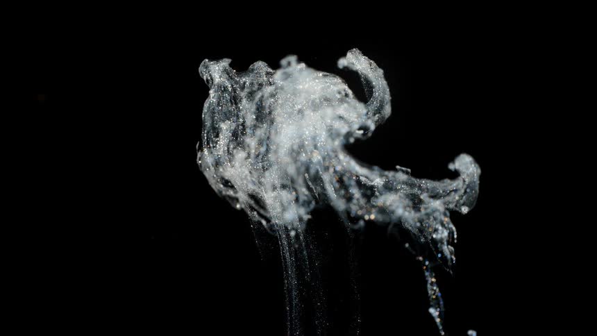 Crystalline particles sparkle while floating upward against black background