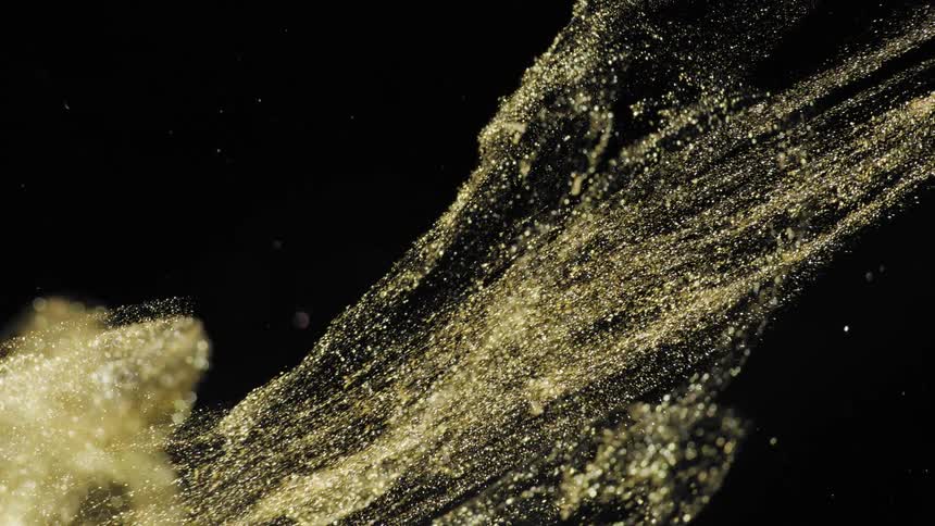 Golden dust clouds move in the dark in the water