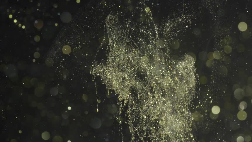 Light spots float across and sparkling particles fall downward black background
