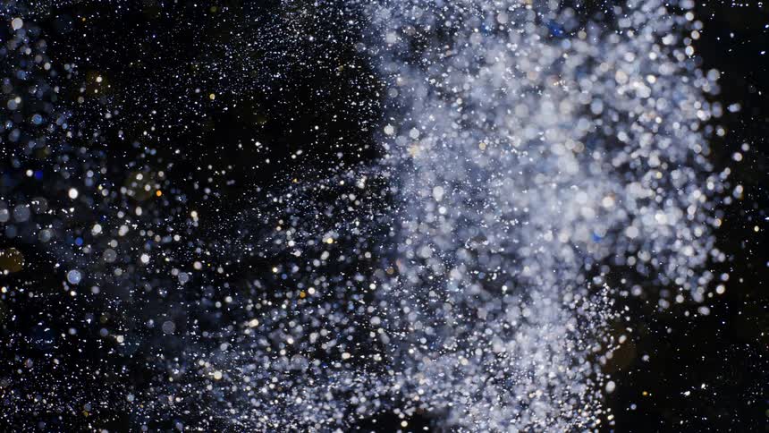 White glitter flows through black as spots glint