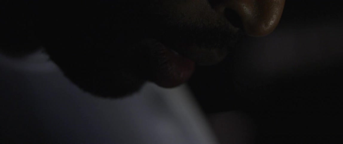 Lips of a man in a dim room looking downward