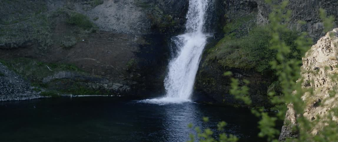 The waterfall pours down on the rocks
