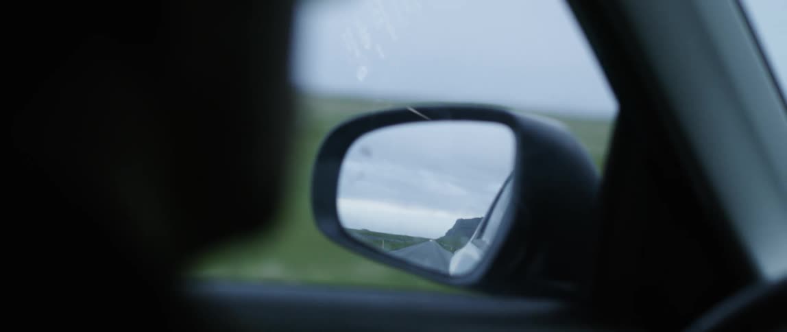 A person drives a car on a rural road