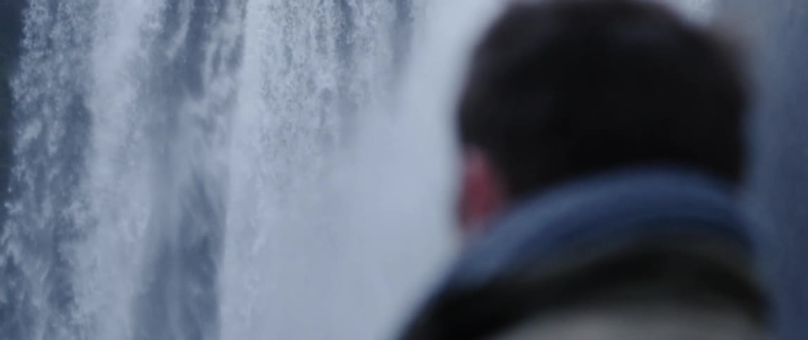 Man wearing a jacket watches the waterfall