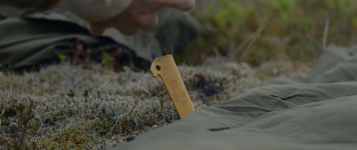 A person pushing down a stake with a rock