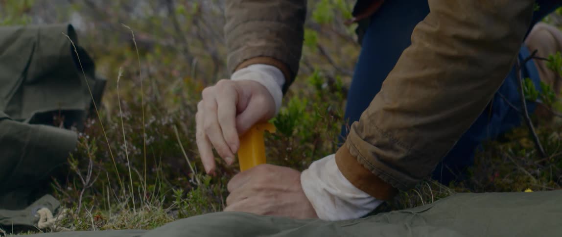 A man puts a stake in the ground while setting up a tent