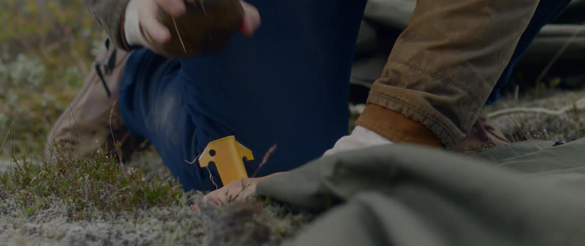 A person hitting a stake with a rock
