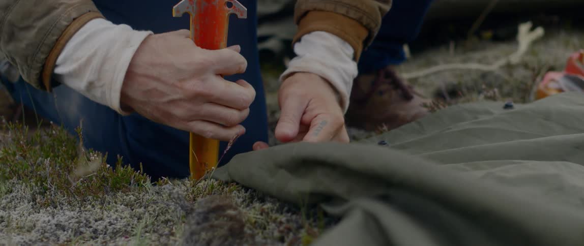 A man puts stakes in the ground to hold down his tent
