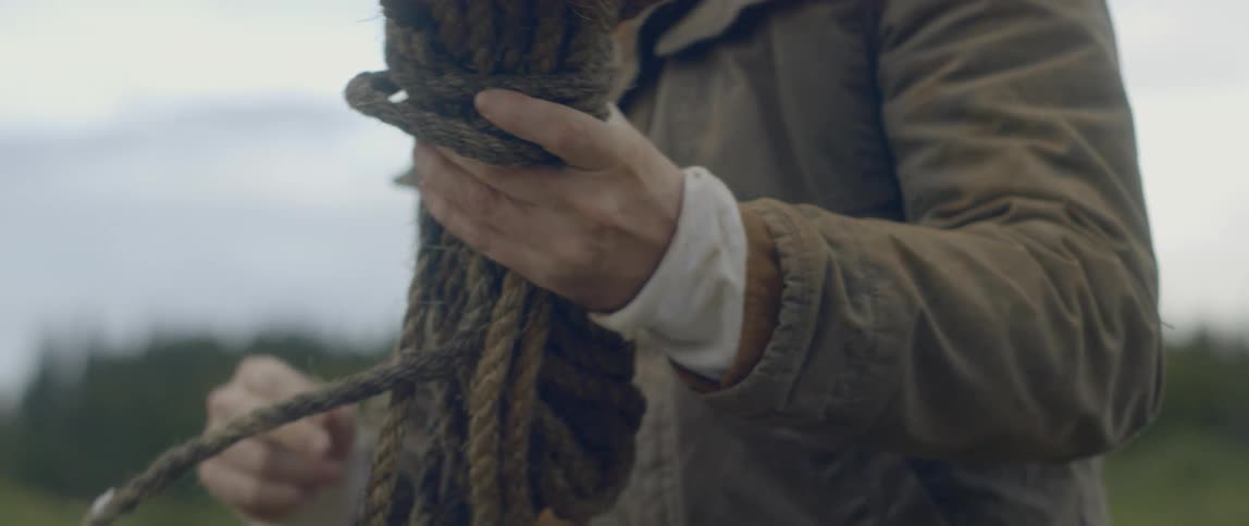 A man unties a long thick piece of rope