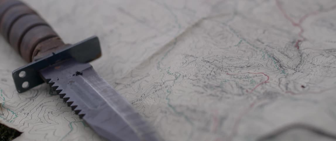 A serrated knife rests on a paper map