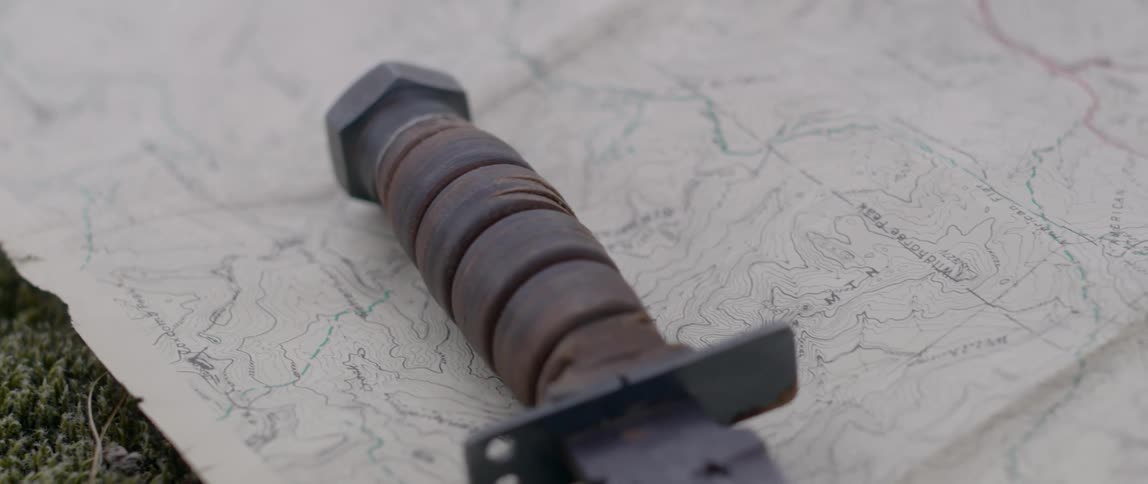 A man sets a knife down on a paper map