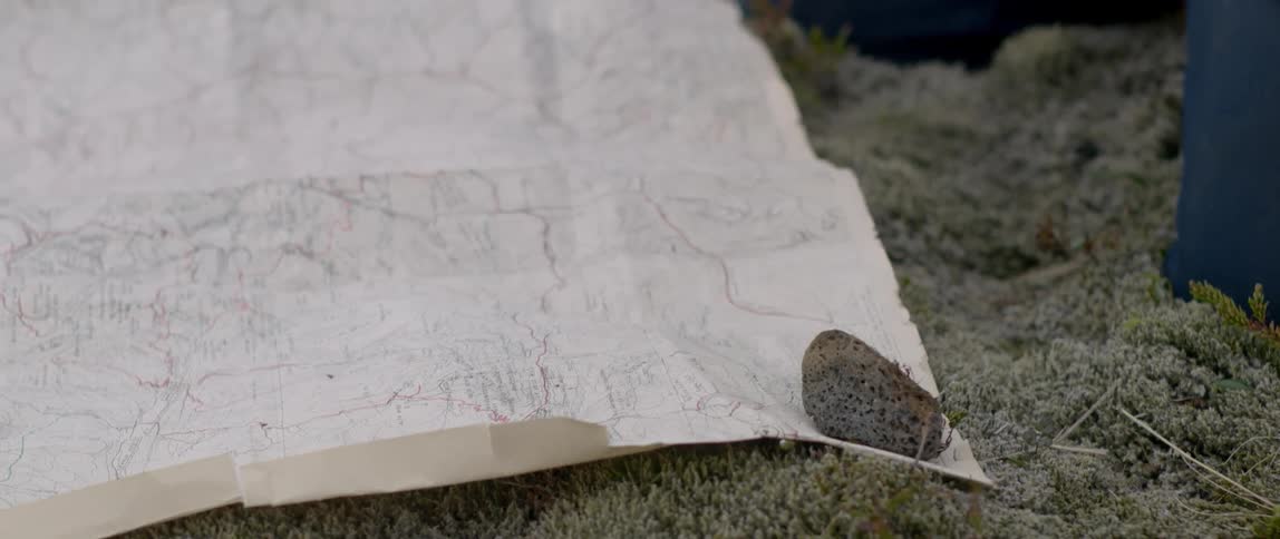 Man placing rock over map outdoors