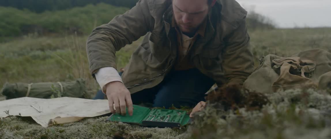 A man quickly opens a small tool case and starts to look for something
