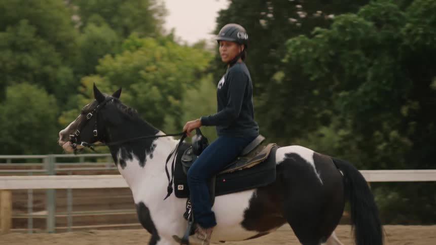 A woman rides a horse around an enclosure during the day
