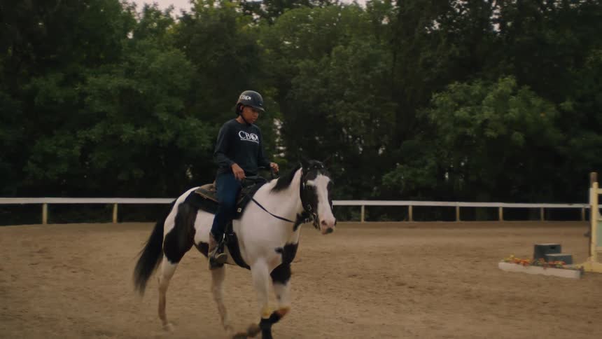 A woman is riding a horse inside a competition pen