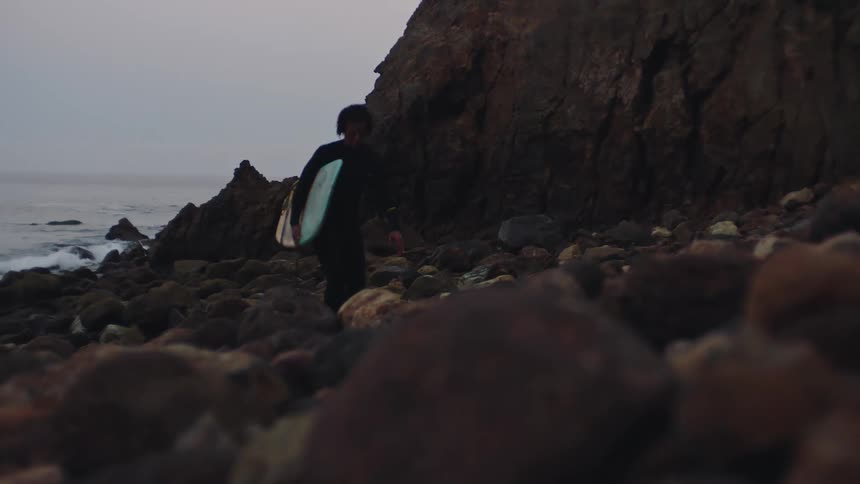 Woman coming out of the sea with a surfboard in his arms