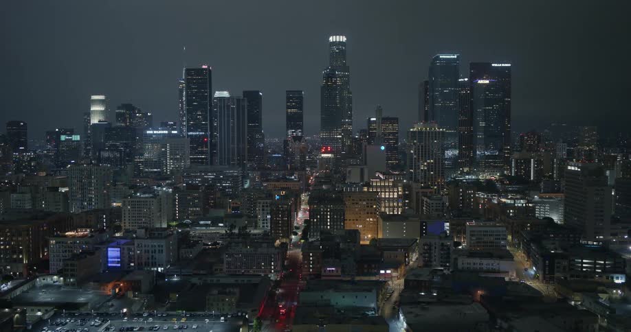 An aerial of lit city buildings at night with tall skyscrapers