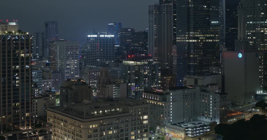 Tall buildings and skyscrapers loom over the streets of a metropolis at night