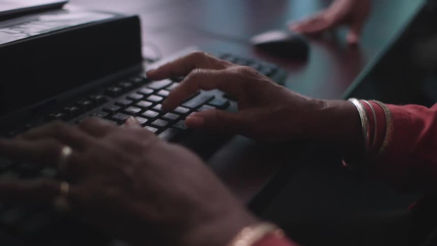 A person types on a computer keyboard while sitting at a table