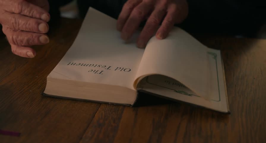 A person sitting at a desk flips through the front pages of a bible