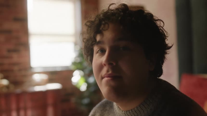 A man smiles while sitting in his apartment