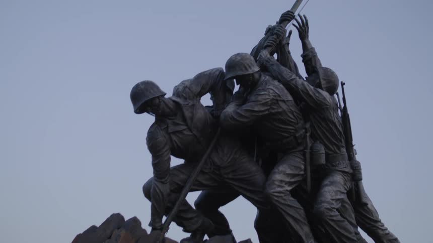 An american flag flies high at the iwo jima memorial on a clear blue day